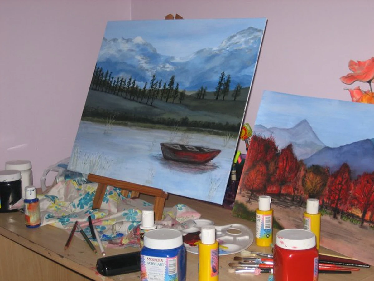 Pinturas de un bote en un lago y un bosque rojo, en el atril